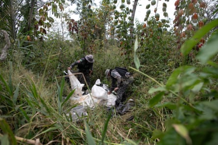 Two members of Brazilian security forces examine bags of ammonium nitrate explosives in a clearing