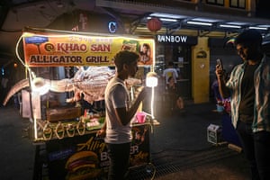 A tourist tries a skewer of alligator meat on Khao San Road in Bangkok
