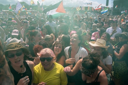 Crowd of mostly women crammed together at Glastonbury show with a Gaza flag blowing in the background