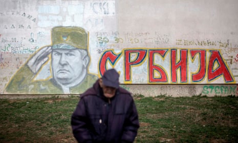 A man stands in front of a graffiti depicting the former Bosnian Serb commander Ratko Mladic in Belgrade.