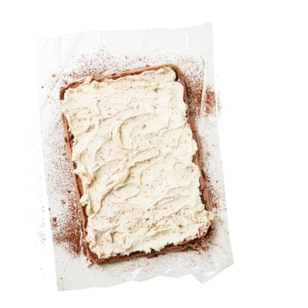 Poser une grande feuille de film alimentaire sur un plan de travail et saupoudrer le tout de cacao en poudre. Retournez délicatement la meringue dessus, longs côtés parallèles aux longs côtés du film alimentaire, puis retournez-la de manière à ce que l'un des petits côtés soit face à vous. Étaler la crème sur tout le dessus de la meringue.