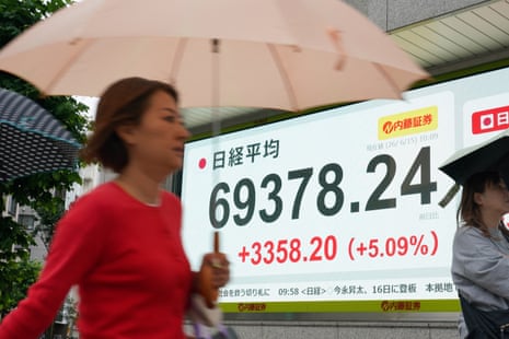 Pedestrians walk past an electronic quotation board displaying the Nikkei Stock Average on the Tokyo Stock Exchange in Tokyo on 15 June 2026.
