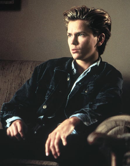 A boy in a dark jacket and denim shirt with slicked-back dark blond hair