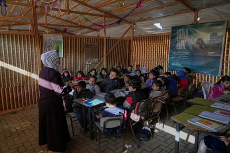 Palestinian children take a lesson in a makeshift classroom located within a school compound in Gaza City.