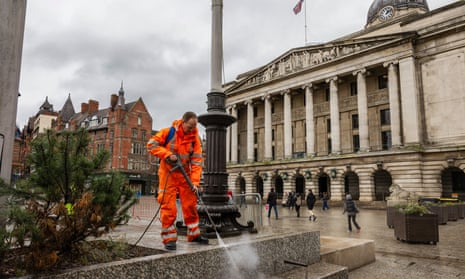 A contractor cleaning Old Market Square in Nottingham with the Council House in the background