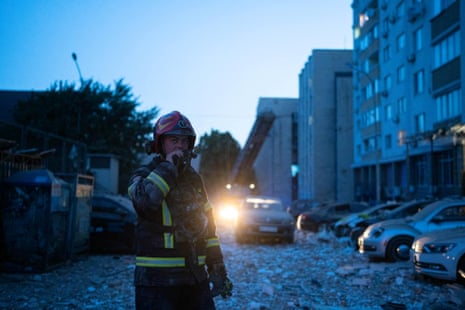 A rescuer works in a rubble-strewn street where an apartment building has been damaged in Kyiv.