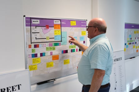 Bob Keiller points at a plan on a wall