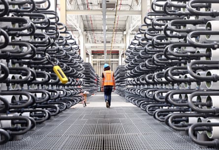 Pipes containing water in a huge warehouse with a staff member wearing orange high vis