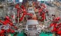 Red-coloured robotic arms work on the car assembly line of new energy vehicles at a factory