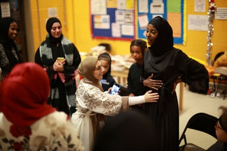 Assma Asif, 25 ans, touche le ventre de Yasmin Abdullahi après avoir annoncé sa grossesse à l'équipe, lors de la fête de fin d'année du Sisterhood FC au Dockland Settlements Community Centre à Londres