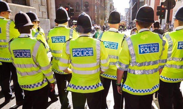 Line of Metropolitan police officers seen from behind.