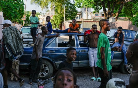 Young men stand around a car parked across a street