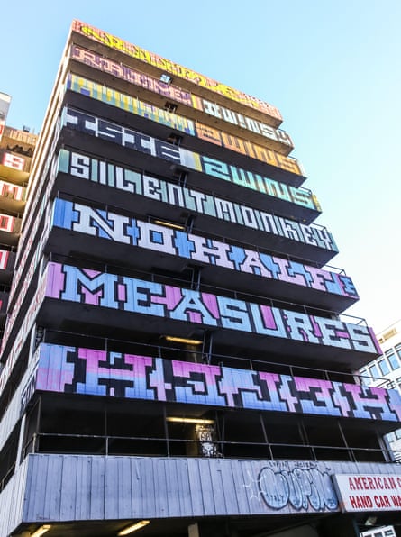 A multistorey car park building covered in lettering on each floor, with Helch written backwards on one tier.