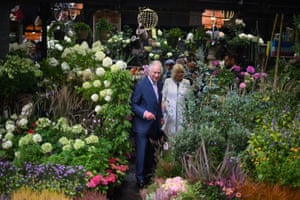 Charles makes his way between plants and flowers, with Camilla following behind