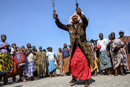A traditional dancer performs in front of the crate containing the Djidji Ayôkwé, as it arrives during the latest repatriation of stolen artefacts in Abidjan.