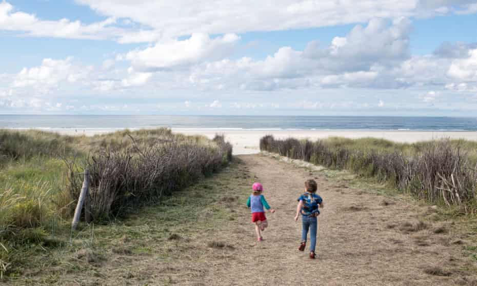 Los niños corren por las dunas hasta la playa en la isla de Juist, Geramny
