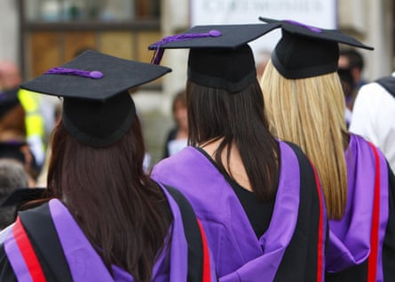 Three women graudates in black gowns and hats with purple and red trim