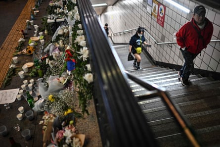 Commuters exit the Itaewon subway station in Seoul on October 30, 2022, while flowers and tributes are seen outside in memory of those who died.