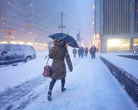 A person walks through a snow storm in a city