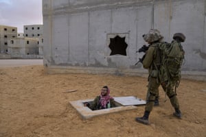Soldiers aim their weapons toward a colleague dressed as a Palestinian militant, while he exits from a fake tunnel