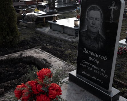 Gravestone with writing in Ukrainian with portrait and red flowers beside