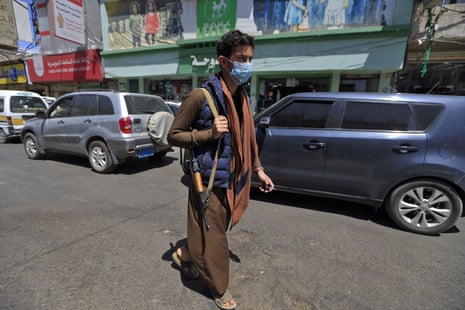 An armed Yemeni man, wearing a protective face mask, walks down a street in the capital Sana’a on 21 March, as the country prepares for an outbreak of coronavirus. 