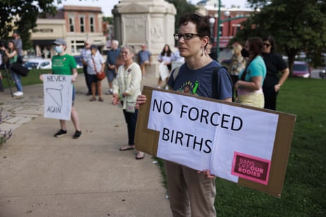 A woman holds a "No Forced Births" sign.