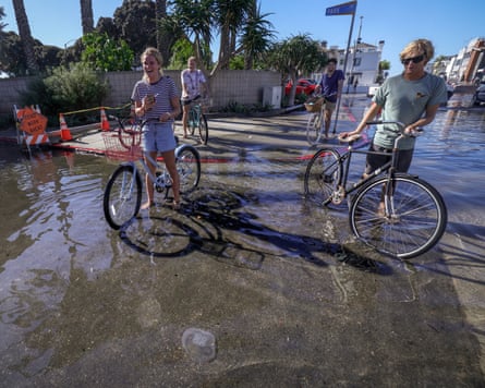 People look at a jellyfish floating in a flooded street in Newport Beach, California.