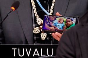 Tuvalu's finance minister, Seve Paeniu, shows a picture of his grandchildren on his phone