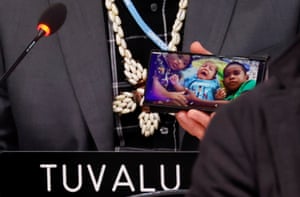 Tuvalu’s finance minister, Seve Paeniu, shows a picture of his grandchildren on his phone