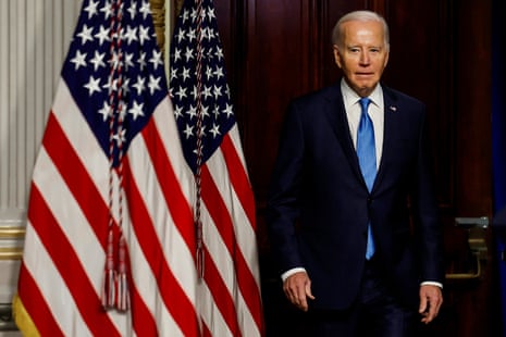 Joe Biden standing in front of American flags
