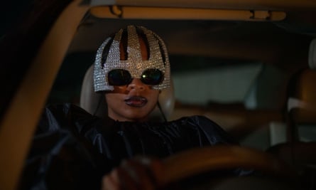 ‘As a film lover, I want more’: the Black female directors taking centre stage A woman drives a vehicle while wearing a jewelled headpiece, in a still On Becoming a Guinea Fowl