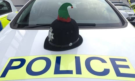 Police officer's helmet with elf hat appendage, on the hood of a police car.