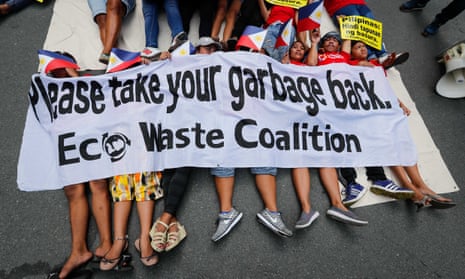 Demonstrators hold placards while lying down on the road during a protest at the Canadian Embassy in the Philippines