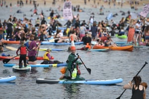 Surfistas, praticantes de paddleboard e caiaque participam de um protesto ambiental nas águas da praia de Gyllyngvase, em Falmouth.