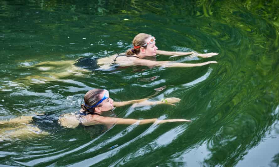 Two women swimming in a river. 