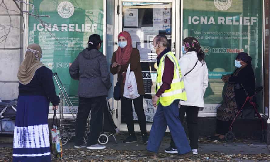 People wear face masks as they wait for an Islamic Circle of North America relief resource center and food pantry to open during the pandemic in November 2020.