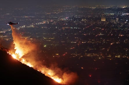 A firefighting helicopter drops water as the Sunset Fire burns in the Hollywood Hills in January