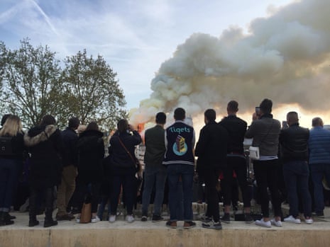 A group watch Notre Dame cathedral burn.