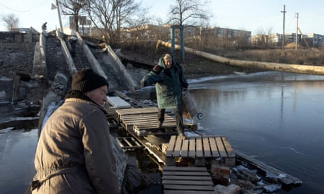 An elderly woman carrying a trolley bag crosses the river on a destroyed bridge in Bakhmut, Donetsk region, on 4 December.