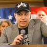 Anthony Constantino speaks into a microphone at a podium, delivering his primary victory speech