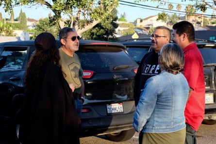 people talk outside near a car