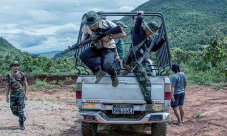 Young men with rifles jump out of a pick-up truck at a clearing in the jungle