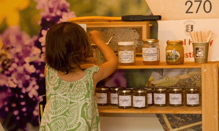 A young girl looks at pots of honey on a shelf in the gift shop at the National Beekeeping Centre Wales.