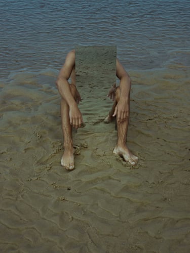 On an Itacaré beach, a mirror reflects sand between a seated person’s bare legs and arms