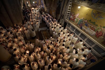 Clerics holding candles walk through the church