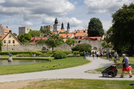 The medieval walls of Visby are seen in the background as people go for a walk around a park