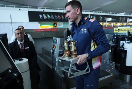 Damiano Lestingi holds the bronze flame holder contraption as he checks in at Heathrow airport