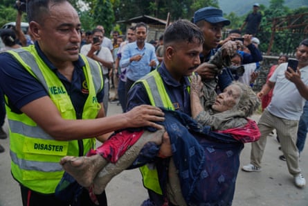 Rescuers carry a victim of the flash flooding to safety along the Trishuli River in Nepal’s Nuwakot district