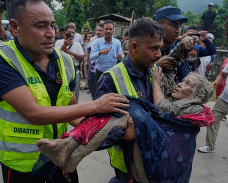 Rescuers carry a mud-covered elderly flood victim to safety in Nepal